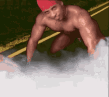 a shirtless man wearing a red bandana is kneeling down