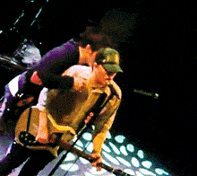 a man in a green hat is playing a guitar on a stage