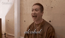 a man in a brown shirt is laughing and the word alcohol is above him