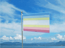 a flag is flying in the wind over a body of water with mountains in the background