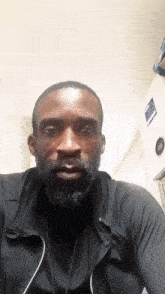 a man with a beard is wearing a black jacket and a black shirt
