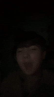 a person is making a funny face in the dark .