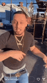 a man wearing a black shirt and a gold necklace with the word king on it