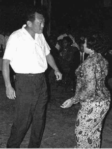 a black and white photo of a man and woman dancing .
