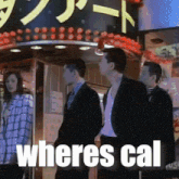 a group of people standing in front of a sign that says " wheres cal "