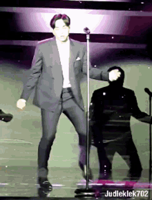 a man in a suit is dancing in front of a microphone with judleklek702 written on the bottom right
