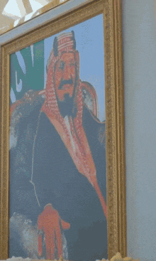 a man sitting in front of a painting of a man with a beard