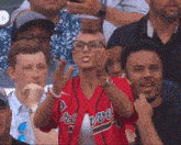 a woman wearing a red braves jersey applauds in a crowd