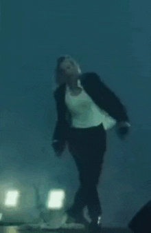 a man in a suit and tie is jumping in the air in the water .