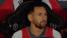 a man with a beard is sitting in a chair with his head on a pillow