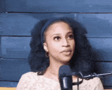 a woman is standing in front of a microphone and making a funny face