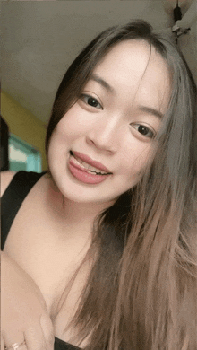 a woman wearing a black tank top is smiling with her tongue hanging out
