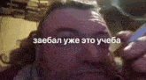 a man with a beard is smoking a cigarette in a video with russian text .