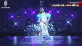 a woman in a white dress is dancing on a stage with purple lights and the words stardom on the bottom