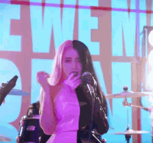 a woman singing into a microphone in front of a large sign that says even
