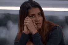 a woman with her hands on her face is looking at the camera with a sad look on her face .