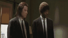 two men in suits pointing guns at a man in a headset