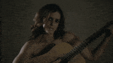 a naked woman is playing a guitar with a dark background