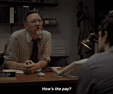 a man sitting at a desk talking to another man with the words how 's the pay