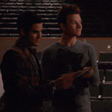 two men are looking at a piece of paper and one has a cat on his shirt
