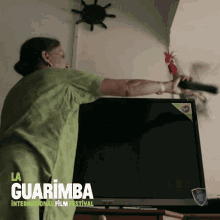 a poster for la guarimba international film festival shows a woman holding a remote