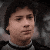 a young boy with curly hair wearing a beanie and a black and white shirt