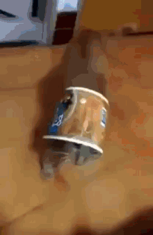 a cat is playing with a can of yogurt on a table