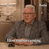 a man sitting at a table with the words how embarrassing on the bottom