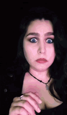 a woman wearing a necklace and a ring looks surprised