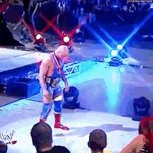 a wrestler is standing on a stage with a medal around his neck in front of a crowd .