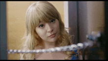 a woman in a blonde wig is looking at herself in a mirror