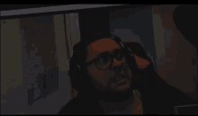 a man wearing glasses and headphones is looking at a computer screen