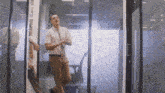 a man in a pink shirt and tie stands in front of a glass door that says exit on it
