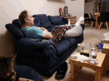 a man is laying on a couch with his legs crossed and a mug that says ' a ' on it