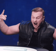 a man in a leather vest is holding something in his hands and screaming