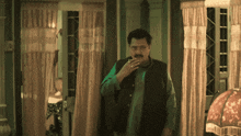 a man smoking a cigarette in a room with curtains