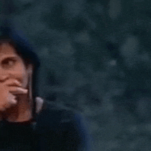 a man is covering his mouth with his hand in a dark room .