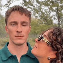 a woman wearing sunglasses is kissing a man 's cheek