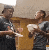 a man wearing a shirt that says chocho on it is talking to another man