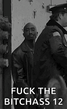 a man in a leather jacket is standing next to a police officer and says `` fuck the bitchass 12 '' .