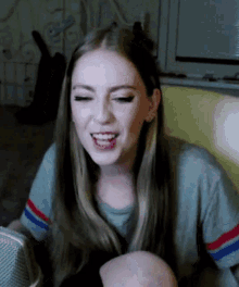 a woman with long hair is sitting in front of a microphone smiling .