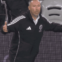 a man wearing a black adidas jacket says what
