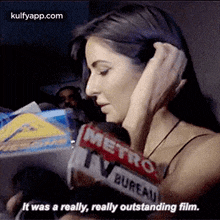 a woman is talking into a microphone while holding a metro newspaper .