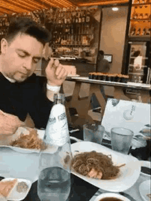 a man is sitting at a table in a restaurant eating food .