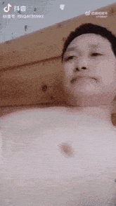 a man without a shirt is laying on a bed with chinese writing on the bottom