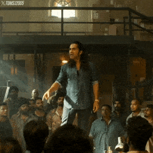 a man in a denim shirt stands in front of a crowd of people with a toms 2005 watermark