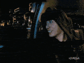 a woman in a hooded jacket is smiling while sitting in a car ..