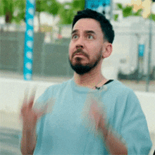 a man with a beard and a blue shirt is making a funny face