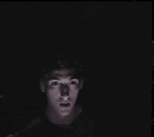 a man is standing in the dark with a shadow on his face .