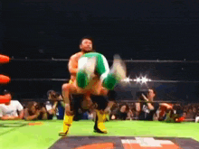 a wrestler in a green outfit is doing a handstand